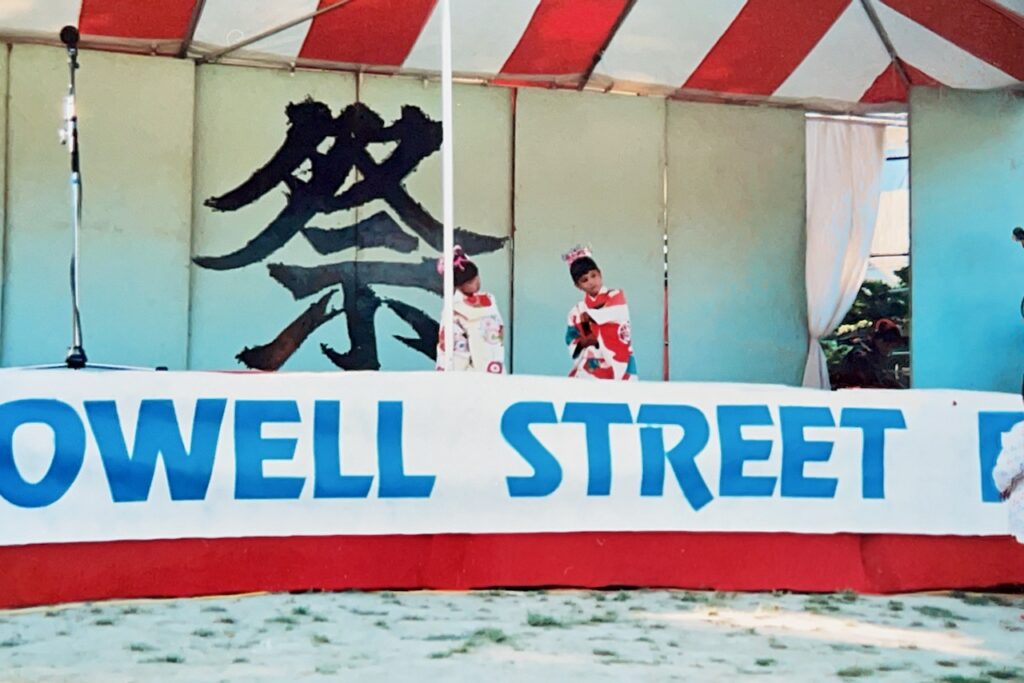 Girls in kimonos dancing behind Powell Street banner